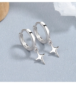 Close-up of 925 silver hoop earrings with polished north star pendants on textured surface