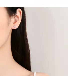 Détail macro de clous d'oreilles croix en argent 925 avec cristaux pavés étincelants