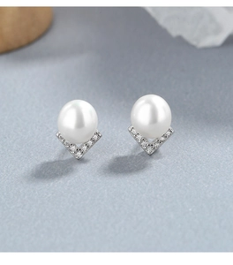 Macro view of 925 silver pearl stud earrings with V-shape diamond-encrusted setting
