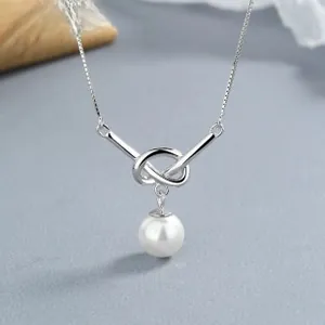 Gros plan du pendentif noeud en argent 925 avec perle blanche sur une chaîne vénitienne