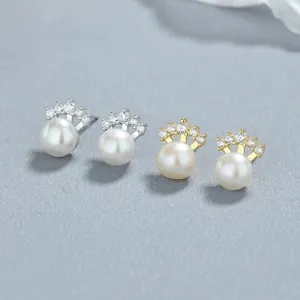 Macro detail of 925 silver and gold pearl stud earrings with zircon crown settings