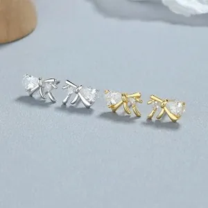 Macro shot of silver and gold bow earrings with pear-shaped cubic zirconia stones