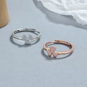 Bagues trèfle en argent et or rose avec anneaux ajustables sur un fond gris texturé