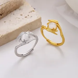 Détail de bagues en bambou or et argent avec pierre oeil de chat sur marbre blanc