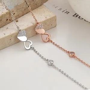 Detail of silver and rose gold heart bracelets featuring interlocking CZ heart pendants