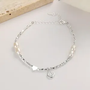 Close-up of 925 silver bracelet with irregular pearls, heart pendant and smiley face charm