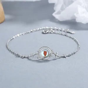 Macro detail of 925 silver planet bracelet with red stone and tiny star charms
