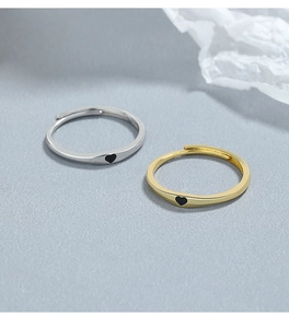 Dettaglio di anelli regolabili in argento e oro con piccoli cuori in smalto nero