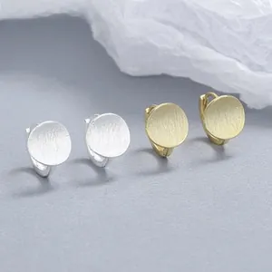 Detail view of gold and silver brushed matte circle earrings with secure hoop closures