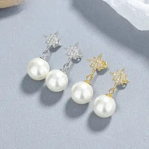 Detailed macro view of gold and silver crown starburst pearl earrings on grey background