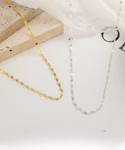 Detailed view of intertwined figure-eight silver and gold necklaces on stone surface