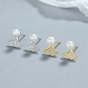 Macro shot of silver and gold ginkgo leaf earrings with tiny crystals and white pearls