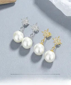 Detailed view of silver and gold starburst pearl earrings with shimmering zircon accents
