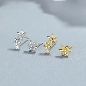 Macro shot of sparkling zircon flower stud earrings in silver and gold finishes