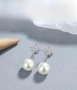 Macro shot of 925 silver star stud earrings with white pearls and sparkling zircons