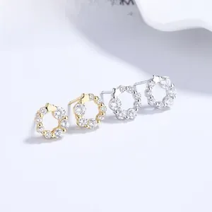 Dettaglio macro di orecchini a lobo in argento 925 con zirconi a corona in oro e argento