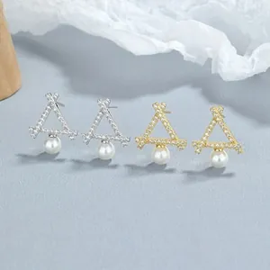 Détail de boucles d'oreilles triangulaires avec zircons incrustés et perles blanches rondes