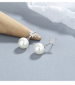 Detailed view of sterling silver star stud earrings with white pearls and pavé stones