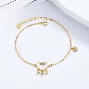 Detailed close-up of golden peace lock bracelet with white shell and heart charm