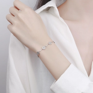 Close-up of elegant 925 sterling silver coin charm bracelet on a female wrist