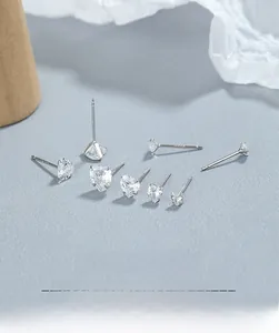Macro shot of 925 silver heart and round cubic zirconia stud earrings set on grey surface
