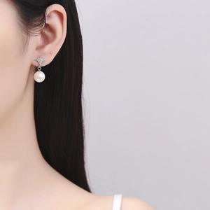Elegant 925 sterling silver starburst pearl drop earrings on model with soft lighting