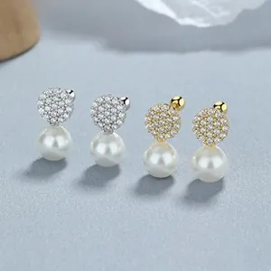 Macro detail of 925 silver pearl stud earrings with pave crystals and screw backs