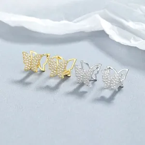 Macro shot of silver and gold butterfly hoop earrings with white zircon micro-inlay
