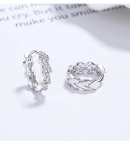 Detailed close-up of 925 silver heart hoop earrings with pavé crystals on white background