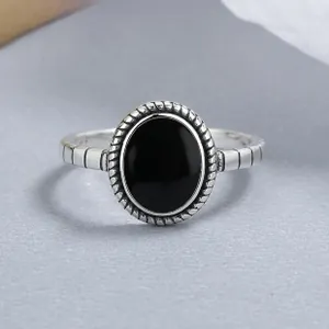 Gros plan d'une bague vintage en argent 925 avec pierre noire ovale et texture torsadée