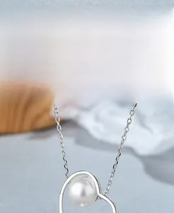 Vue détaillée du pendentif cœur évidé en argent S925 avec une perle blanche élégante