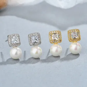Detail of 925 silver and gold pearl earrings featuring square-cut cubic zirconia clusters