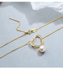 Détail macro du pendentif cœur doré avec perle et chaîne à aiguille réglable