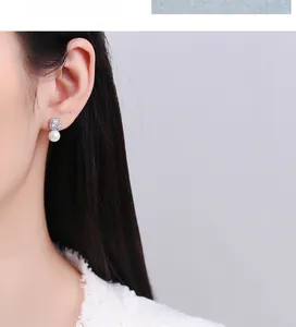 Close-up of model wearing square micro-pave diamond stud earrings with elegant white pearl