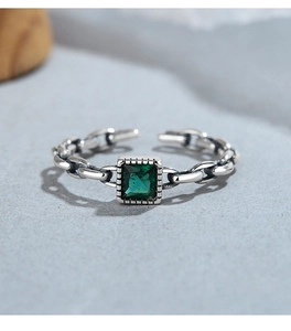 Macro shot of 925 silver chain ring featuring an emerald-green square gemstone