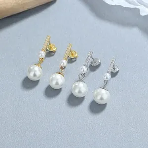 Macro view of teardrop pearl drop earrings in gold and silver finishes with micro-pavé crystals