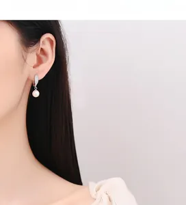 Gros plan d'un mannequin portant d'élégantes boucles d'oreilles en argent 925 et perles avec zircon