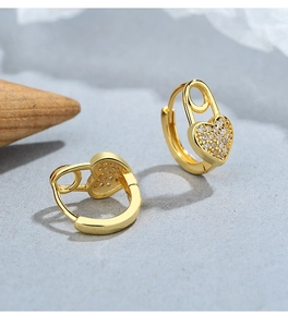 Dettaglio macro degli orecchini a cuore a spilla dorati con zirconi bianchi micro-pave