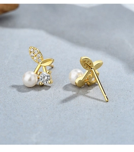 Macro view of 925 silver cherry pearl earrings with gold leaf and zircon details