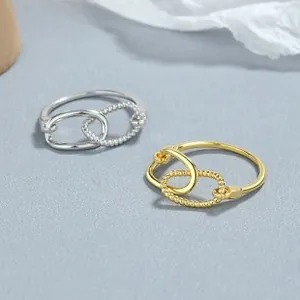 Détail de bagues entrelacées en argent et or avec anneaux lisses et texture perlée