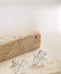 Macro view of S925 sterling silver hollow bow earrings on a natural stone surface