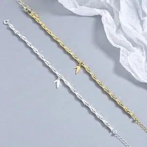 Detailed view of bamboo-shaped bracelets in silver and gold with small leaf pendants