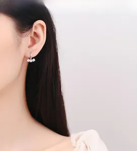 Primo piano di una modella che indossa orecchini a cerchio in argento 925 con tre zirconi