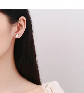 Close-up of 925 silver clover stud earrings with sparkling cubic zirconia on a model