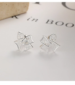 Macro shot of 925 sterling silver bow earrings featuring intricate hollow-out lace design