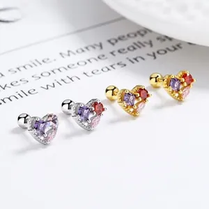 Close-up of heart-shaped zircon earrings with screw back design in gold and silver