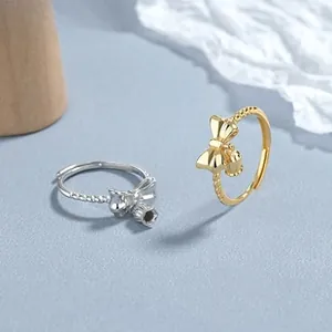 Detailed view of silver and gold bow rings with bell charms and beaded texture