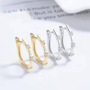 Macro detail of 925 silver bamboo hoop earrings with sparkling zircon stones in gold and silver