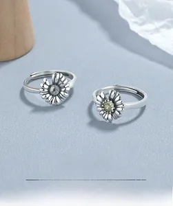 Macro shot of 925 sterling silver daisy rings with adjustable bands on blue surface