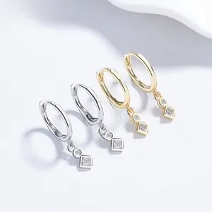 Macro detail of geometric silver and gold earrings with vertical cubic zirconia stones